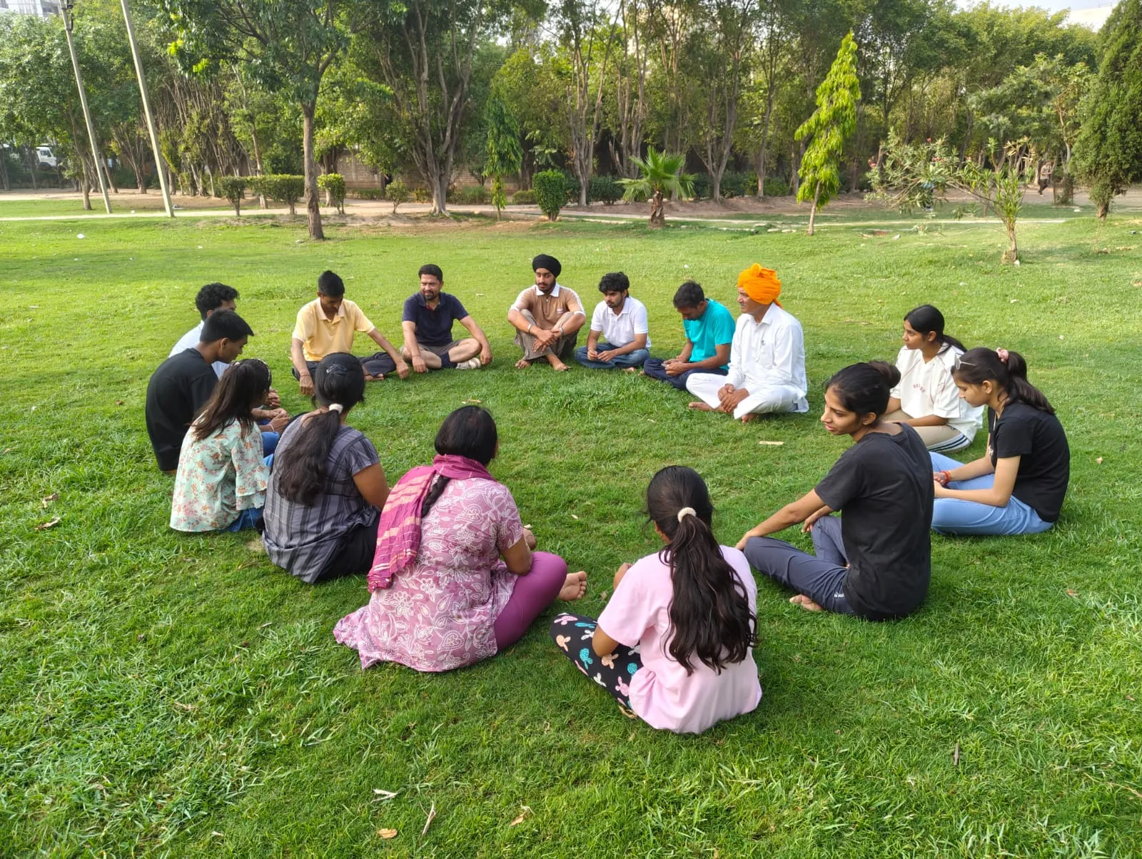 Volunteers and students sitting in a circle for a meditation session in a park
