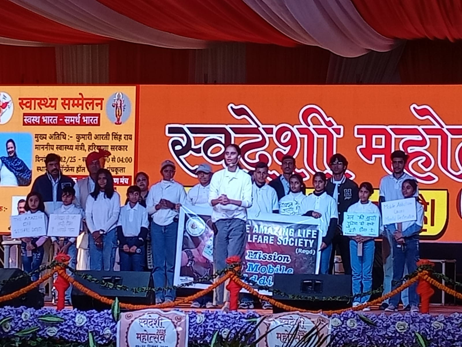 Volunteers and children on stage at a public awareness event