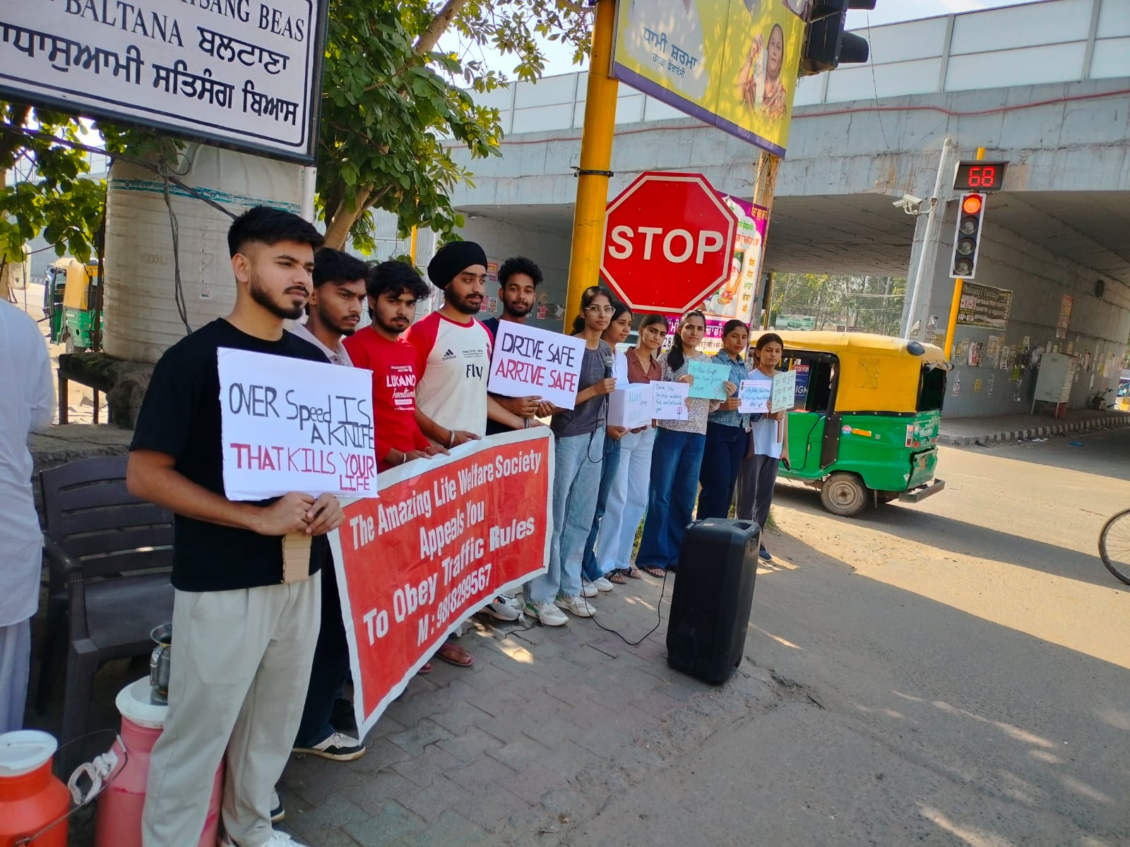 Volunteers holding road-safety placards under a flyover
