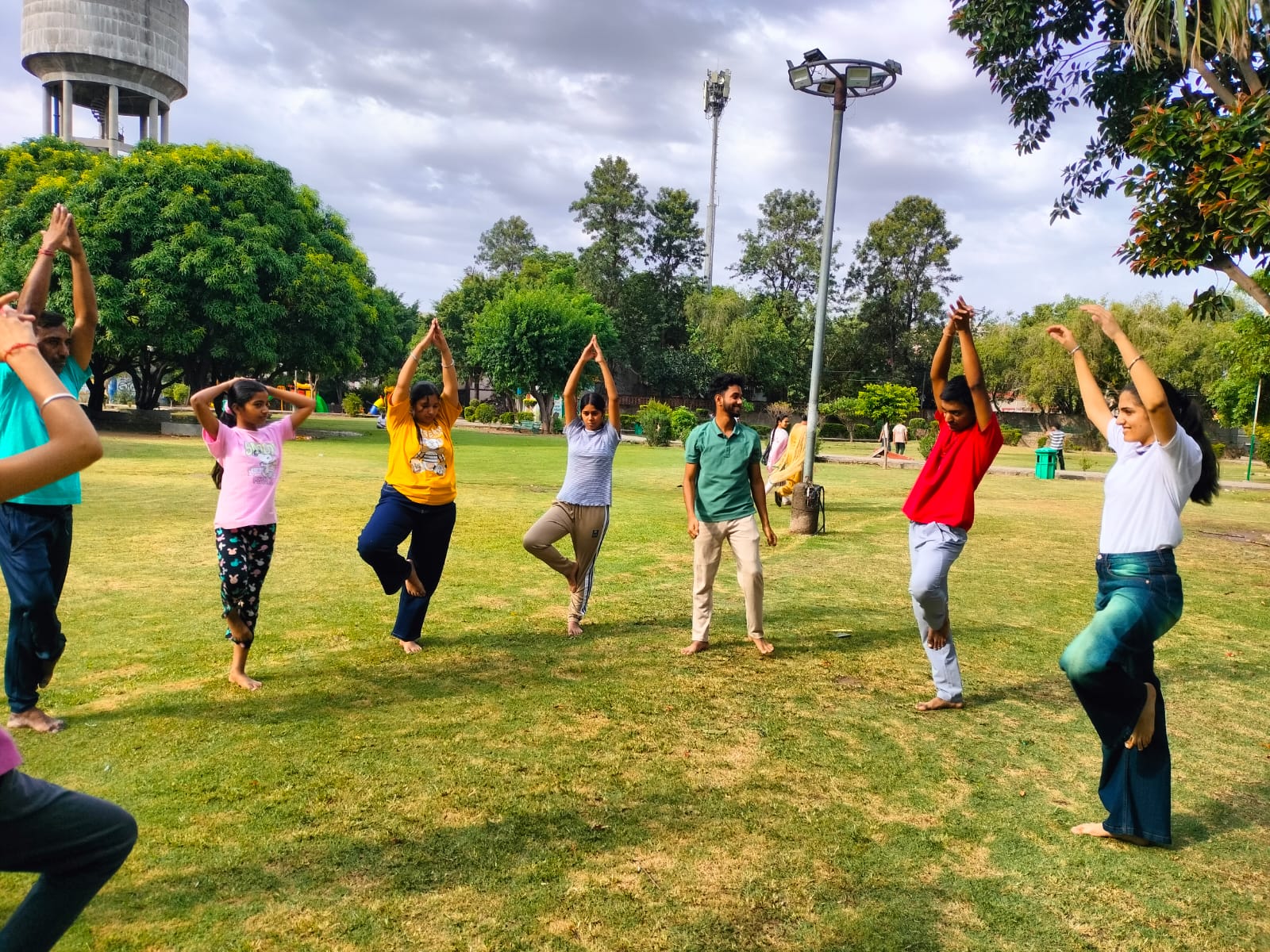 Volunteers and children practising yoga together outdoors